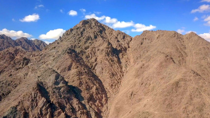 Desert landscape - Aerial image of mountains and dry land with blue cloudy sky in the background.