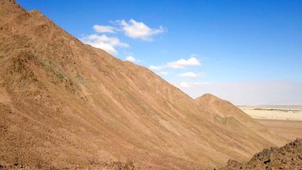 Desert landscape - Aerial image of mountains and dry land with blue cloudy sky in the background.