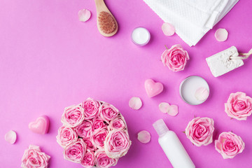 Aromatherapy, spa, beauty background with roses flowers, cosmetics and candles on pink table. Flat lay style.