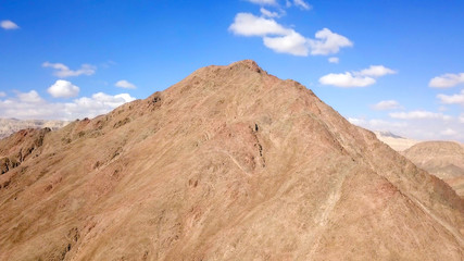 Desert landscape - Aerial image of mountains and dry land with blue cloudy sky in the background.