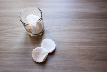 Containers of cotton health care supplies over wooden background