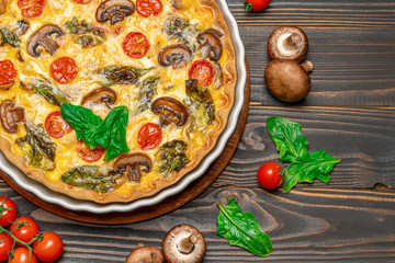 Baked homemade quiche pie in ceramic baking form on concrete background
