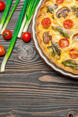 Baked homemade quiche pie in ceramic baking form on concrete background
