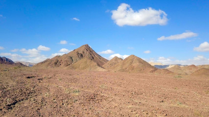 Desert landscape - Aerial image of mountains and dry land with blue cloudy sky in the background.