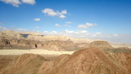Desert landscape - Aerial image of mountains and dry land with blue cloudy sky in the background.