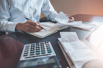 Woman with bills and calculator. Woman using calculator to calculate bills at the table in office....
