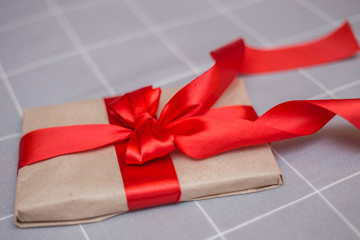 Kraft paper envelope tied with a red ribbon as a gift message. Gift tied with a red bow on a gray...