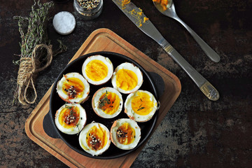 Soft-boiled eggs halves in a cast-iron skillet. Flat lay.