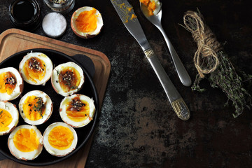 Soft-boiled eggs halves in a cast-iron skillet. Flat lay.