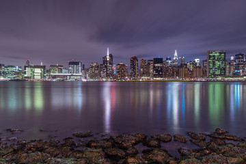 Fototapeta na wymiar View on Midtown manhattan from east river with rocks on foreground at night,long exposure shot