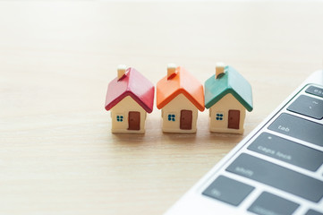 Miniature houses mortgage next to modern laptop with copy space, Real estate online investment and business house loaning marketing on internet.