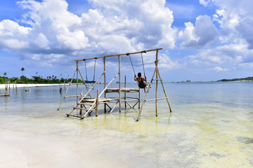 Indonesian girl on a swing in a beach of Pantai Tanjung Kelayang, Belitung Island, Indonesia
