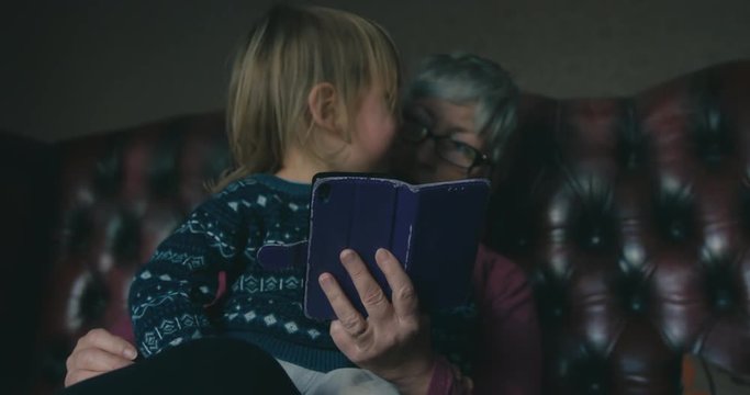 Little toddler and grandmother looking at smartphone