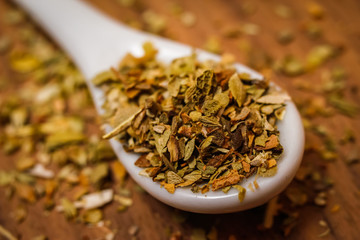 Dried oregano spice in a spoon. Extreme macro photography.