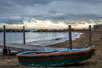 A lonely boat on the beach of Castiglioncello in Tuscany in winter at sunset with an island on the horizon