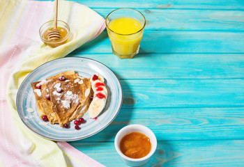 Traditional crepes with banana and berries on blue wooden background.