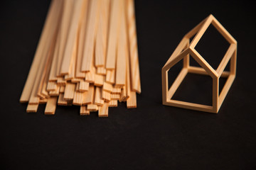 Miniature model of wood frame house with pile of wooden planks