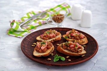 Bruschetta with duck confit pate, apple chutney and caramelized pumpkin seeds. Selective focus.