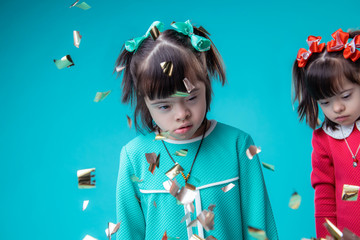 Dark-haired unusual girls with face features standing while confetti falling