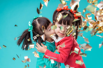 Dark-haired positive sisters kissing each other while standing