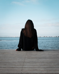Imagen de una chica joven de espaldas mirando hacia el mar en el Delta del Ebro en Tarragona