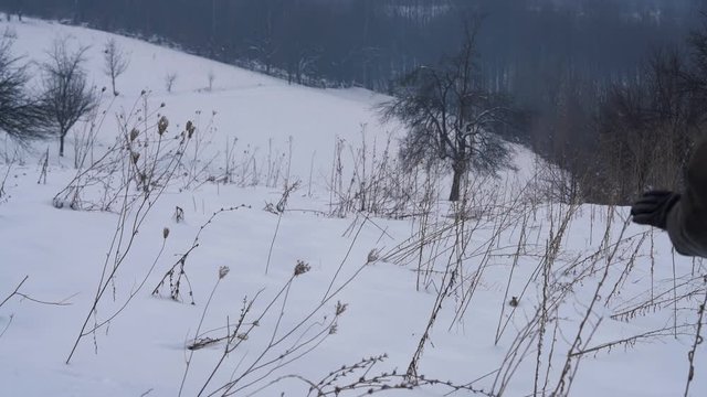 Man goes through dry wildflowers in deep snow - (4K)