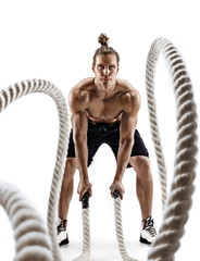 Handsome strong man working out with heavy ropes. Photo of man in sportswear isolated on white...