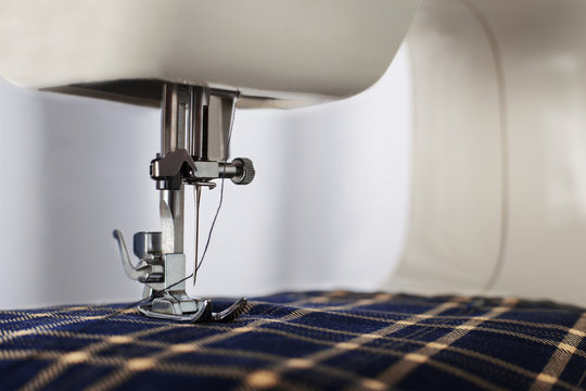 Sewing machine with needle, thread and fabric. Item of clothing. Sewing industry.