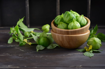Fresh organic green tomatillos (Physalis philadelphica) with a husk on rustic wooden table.