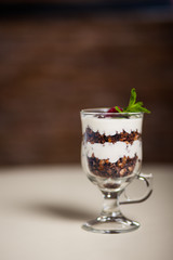 Yogurt with cream, strawberry and muesli served in glass on the table