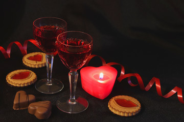 Two crystal glasses of wine, candles and sweets. Red is the color of passion. Romantic date. Be my Valentine