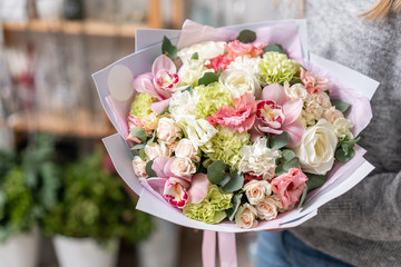 beautiful fresh cut bouquet of mixed flowers in woman hand. the work of the florist at a flower shop. Delicate Pastel tones color