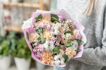 beautiful fresh cut bouquet of mixed flowers in woman hand. the work of the florist at a flower shop. Delicate Pastel tones color