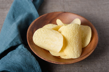 Crispy potato chips in wooden bowl with napkin