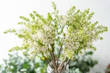 Bunch white lilac in glass vase. Bouquet flowers on light background. Wallpaper. Spring flowering trees