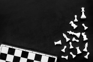 Symbol of competition. Chess board and chess figures on black background top view copy space