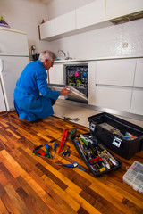 Old age workman fixing the dishwasher machine