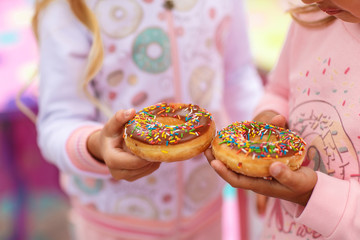 two girls are holding a sweet and a big donut