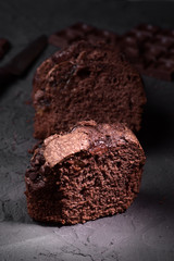 chocolate cake cut with knife and cocoa beans on rough gray background