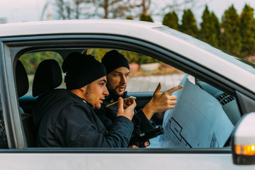 Two Thieves parked in an ally waiting while talking on the phone, observing their target and...