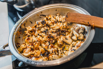 Chicken fillet slices, fried onions and carrots in a cream sauce in a pan - close-up - home cooking