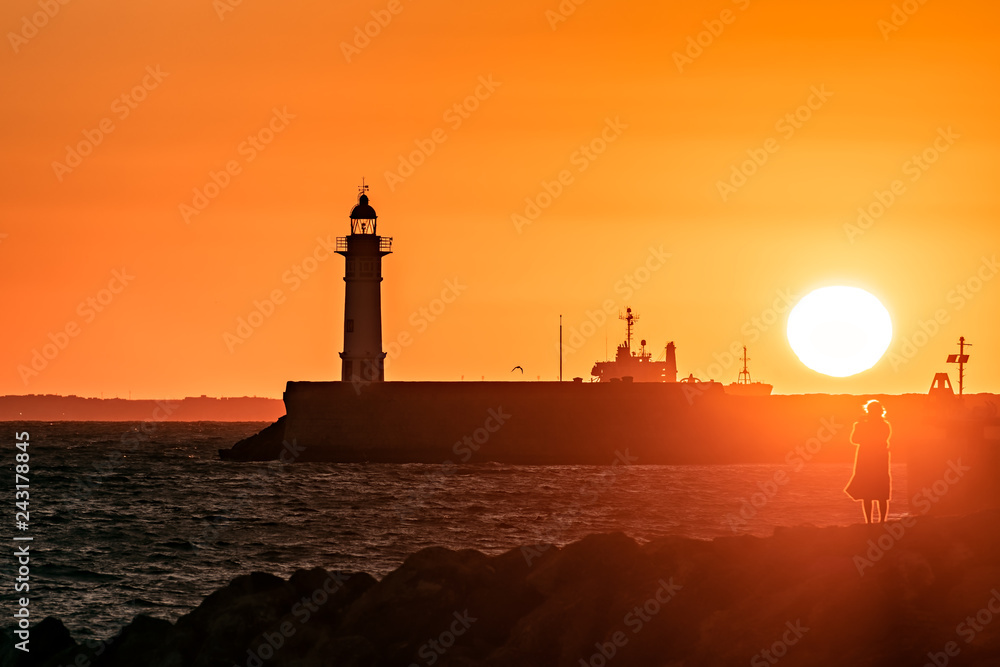 Wall mural Coastal sunset scene with lighthouse; back light.