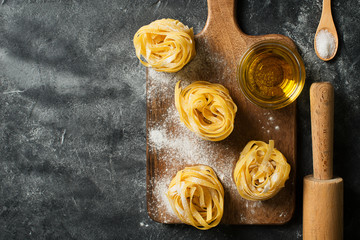 Tagliatelle pasta uncooked, making spaghetti background, black texture