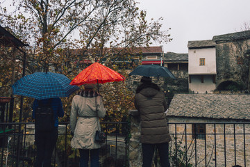 Three people with umbrellas. Street in Mostar. - 243180849
