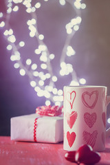 Valentine's day concept with cup of hot drink over shining background