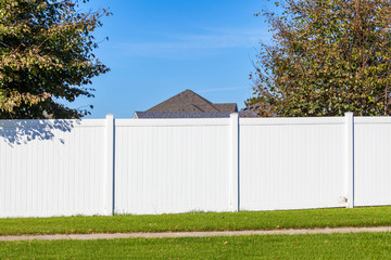 White vinyl fence spanning across the back yard of a home