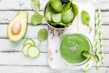Healthy green smoothie with spinach, avocado, banana and chia seeds in glass jars on white wooden...