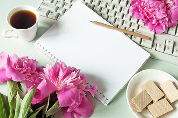 computer keyboard, notepad, pen, cup of coffee, waffles and peony bunch
