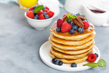 Stack of fluffy pancakes with fresh berries and pecan nuts