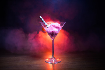 Martini glass filled with colorful fruit ice cream on dark background with toned light and fog